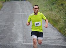 a man running down a road in the rain with an expression on his face as he runs