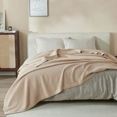 a bedroom with a bed, nightstands and pictures on the wall above it in neutral colors