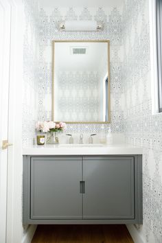 a bathroom vanity with a mirror above it and flowers on the counter top in front of it