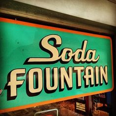 a sign that says soda fountain on the side of a building