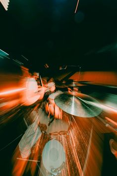 a blurry image of drums in motion on a drum set, with the lights from behind them