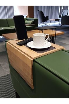 a cell phone sitting on top of a table next to a cup and saucer