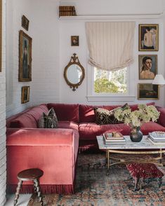 a living room with red couches and pictures on the wall above them, along with a coffee table