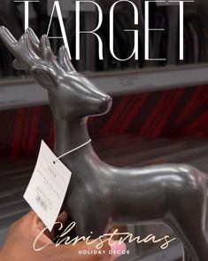 a person is holding a tag in front of a silver deer statue that reads target christmas holiday decor