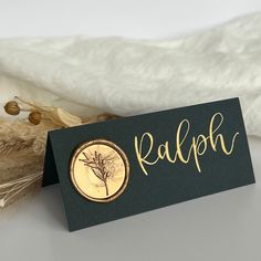 a close up of a sign on a table near some dried flowers and wheat stalks