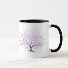 a white and black coffee mug with a pink tree on the inside, in front of a marble surface