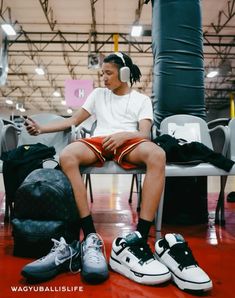 a young man sitting on top of a chair next to a bag and headphones