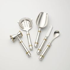 silver and gold utensils are arranged on a white surface