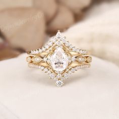 an engagement ring with a pear shaped diamond surrounded by smaller round brilliant cut diamonds and gold band