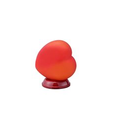 an orange object sitting on top of a red stand against a white background in the shape of a heart