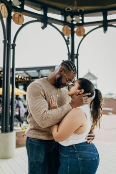 a man and woman embracing each other in front of a gazebo at an amusement park