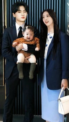 two people standing next to each other holding a baby