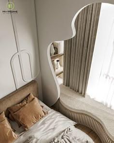 a large bed sitting next to a tall window in a white room with curtains on the windowsill