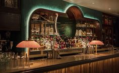 a bar with several bottles and glasses on the counter, along with two lamps in front of it