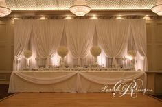 a banquet hall decorated with white drapes and chandeliers