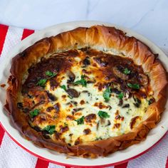 a cheesy dish in a white bowl on a red and white table cloth