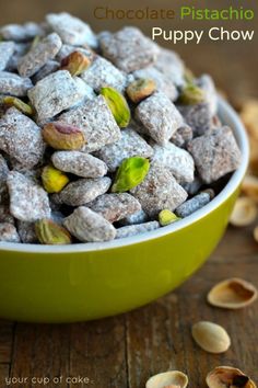 a green bowl filled with nuts on top of a wooden table