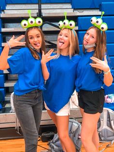 three girls in blue shirts are posing for the camera with silly hats on their heads