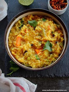 a bowl filled with rice, carrots and cilantro on top of a table