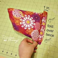 someone is cutting out fabric with scissors and a piece of cloth that has flowers on it