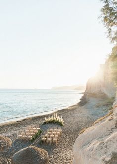 an outdoor ceremony setup on the beach with chairs set up in the sand and flowers