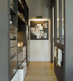 a narrow kitchen with open shelving and wooden flooring is shown in this image