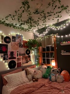 an unmade bed with many stuffed animals on it and lights strung from the ceiling