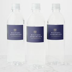 three water bottles with labels on them sitting on a marble countertop in front of a white background