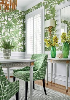 a dining room with green chairs and wallpaper on the walls in front of a table