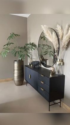 there is a mirror and some plants on the dresser in this room with grey walls