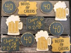 decorated cookies with beer and cheers written on them are displayed in front of a wooden board