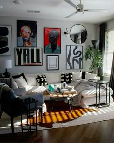 a living room filled with white furniture and pictures on the wall above it's windows