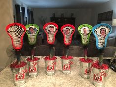 there are many lacrosse goalies in the buckets on this counter top, and one is decorated with an image of two men's faces