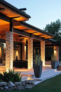 a modern house with large planters and lights on the front porch, along with an outdoor seating area