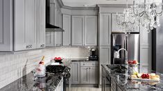 a kitchen with marble counter tops and stainless steel appliances, along with chandelier hanging from the ceiling