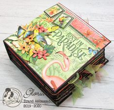 a close up of a box on a wooden surface with flowers and leaves around it