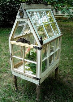 an old greenhouse is turned into a planter in the yard with plants growing inside