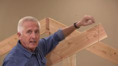 an older man standing in front of a wooden cross