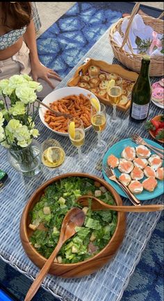 a table filled with food and drinks on top of a blue cloth covered picnic table