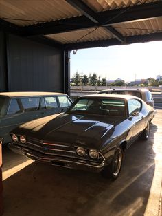 two cars parked in a garage next to each other under a roof covering over them