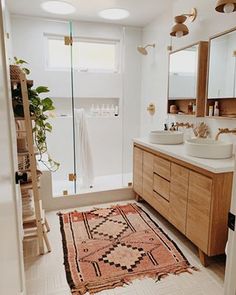 a bathroom with two sinks and a large rug on the floor in front of it