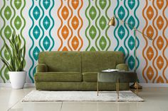 a green couch sitting in front of a wall with an orange and blue pattern on it