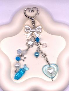 a keychain with charms attached to it on a white plated surface in the shape of a heart