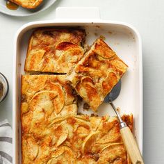 a pan with some food on top of it next to a spoon and cup of coffee