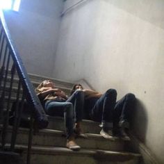 three people are sitting on the stairs in an old building and one person is laying down