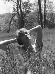 black and white photograph of a woman in a field with her arms behind her head