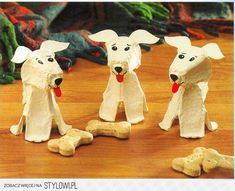 three white dogs made out of toilet paper on a table next to some dog bones