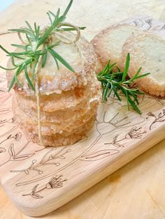 two pastries sitting on top of a wooden tray covered in powdered sugar and sprigs