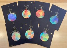 four christmas ornaments are hanging from string on black cards with colorful tie - dyed paper