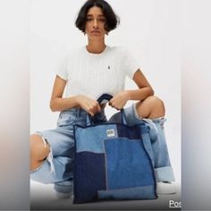 a woman sitting on the ground holding a blue bag